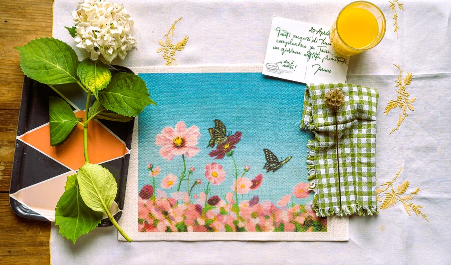 Una tovaglietta che immortala il delicato volo di farfalle sopra un prato fiorito, con il tratto artistico di Jung Eon Hwang che evoca la bellezza naturale e l'armonia della natura.