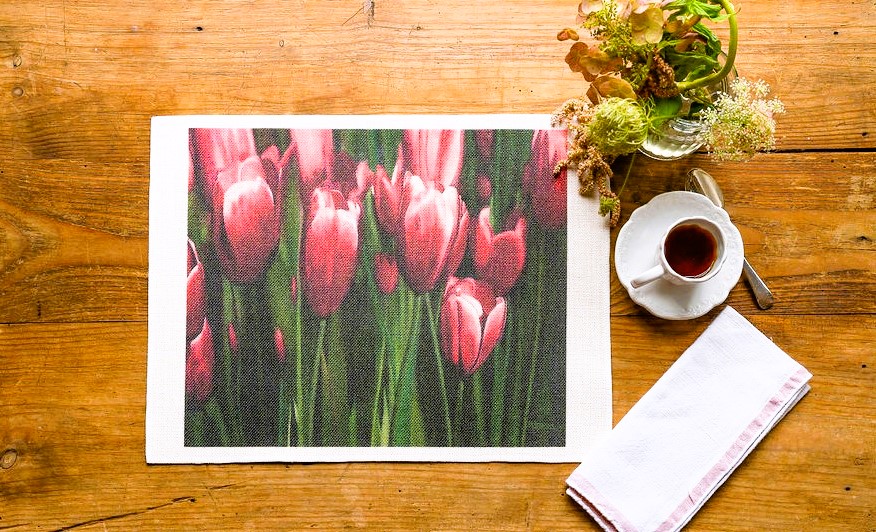 Una tovaglietta che mostra un vaso di tulipani in tutta la loro bellezza. L'artista Martin Charl Sodoms cattura la finezza di ogni fiore con una maestria che mette in risalto la loro grazia.