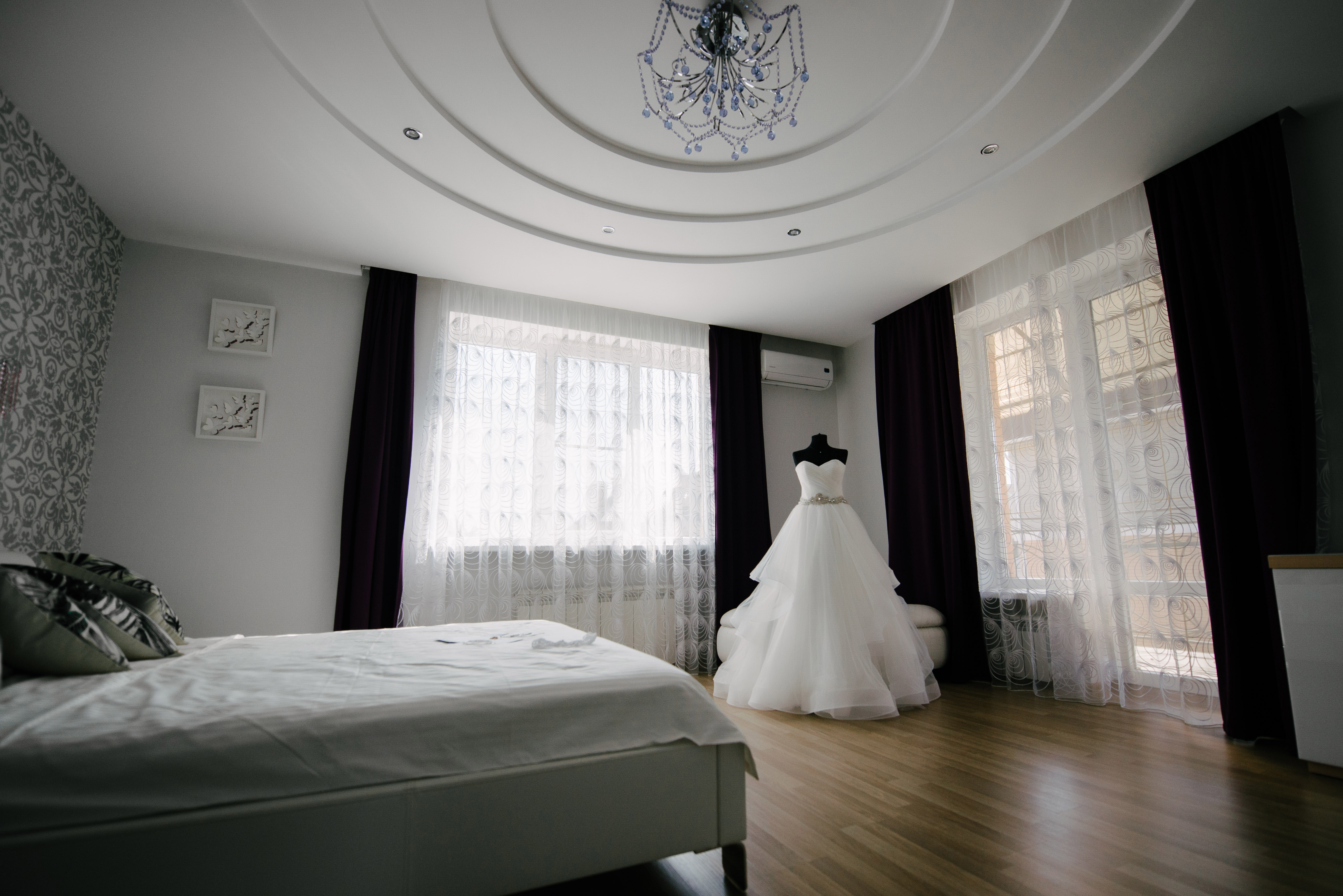Un vestito da sposa bianco appeso in una stanza luminosa.
