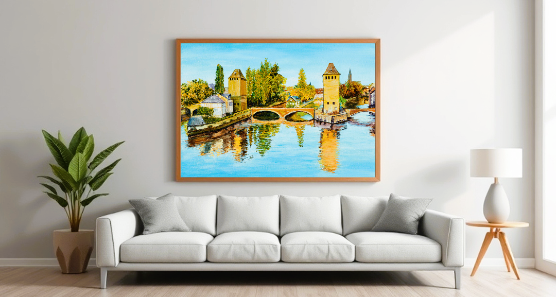 Soggiorno moderno con divano grigio e un grande quadro paesaggistico che raffigura un corso d'acqua con ponti e torri, creando un'atmosfera serena e raffinata nell'ambiente.